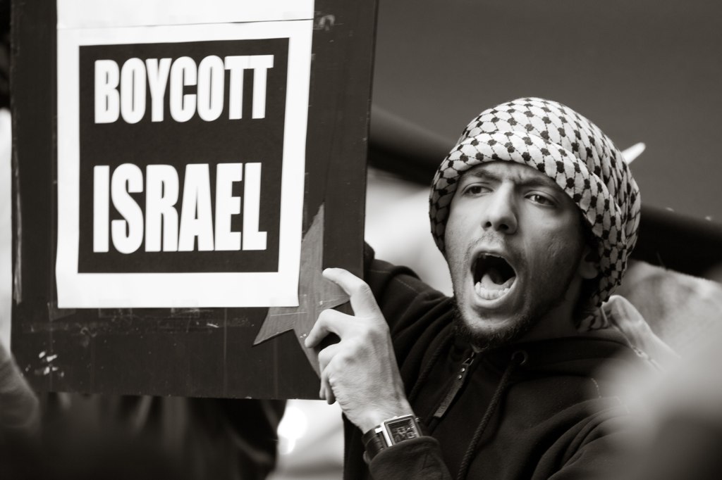 متظاهر في أحدى مظاهرات دعم فلسطين يرفع يافطة تدعوا لمقاطعة "إسرائيل"، الصورة: Richard Ashurst (flickr)